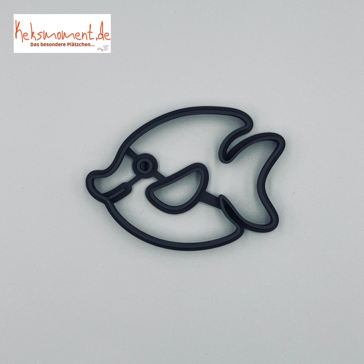 Fisch-Ausstecher in der Draufsicht auf hellem Hintergrund; runde Augenlinie, lächelndes Maul und geteilte Schwanzflosse.