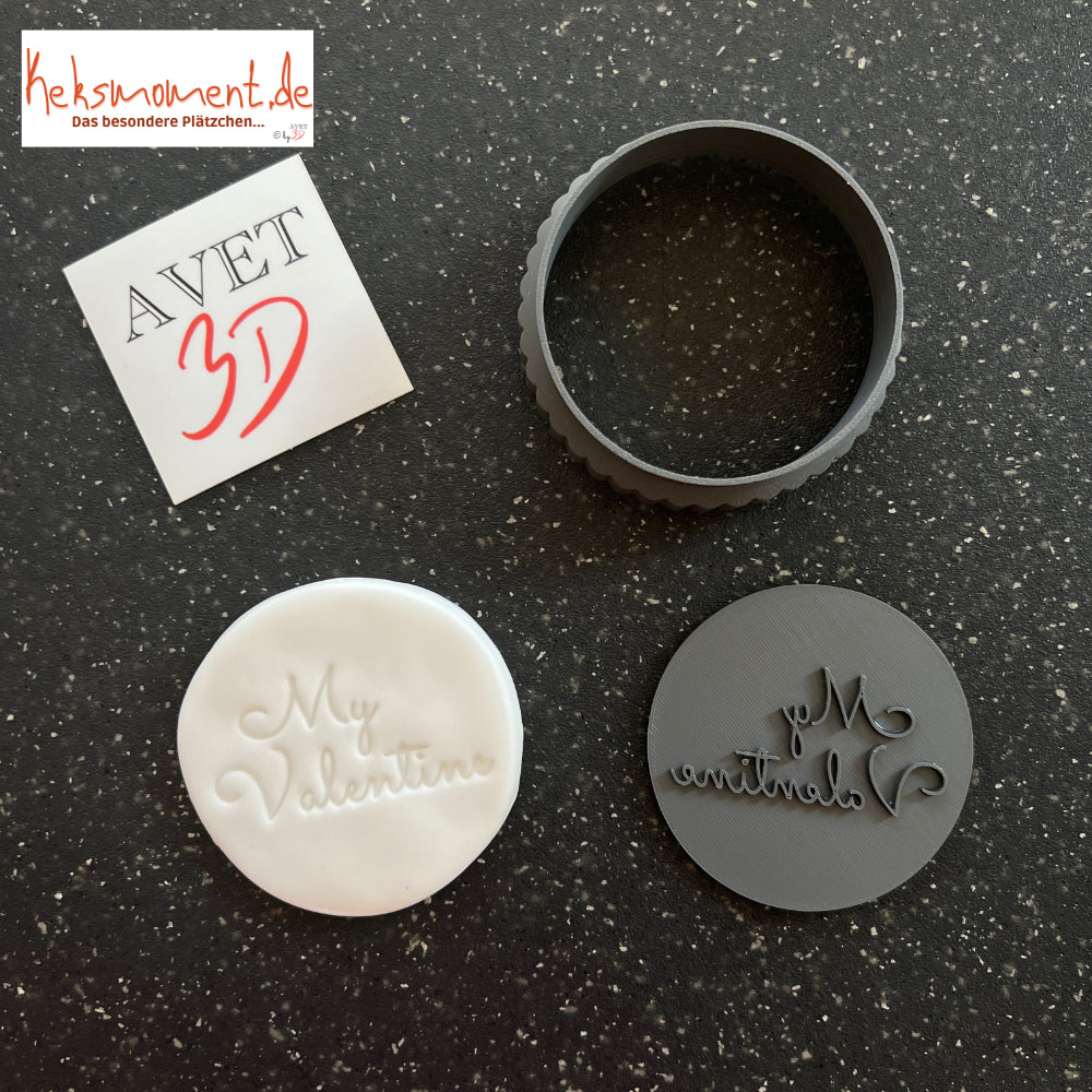 Runder Schriftstempel mit spiegelverkehrtem Valentinsgruß neben einer hellen geprägten Scheibe und rundem Ausstechring.