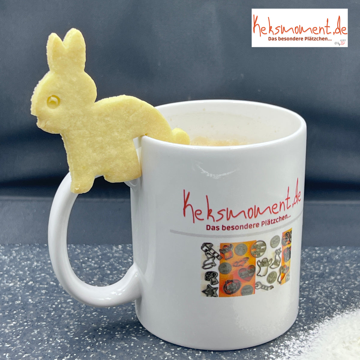 Helles Hasenmotiv mit langen Ohren und eingeprägtem Auge am Rand einer bedruckten weißen Tasse vor dunklem Hintergrund.