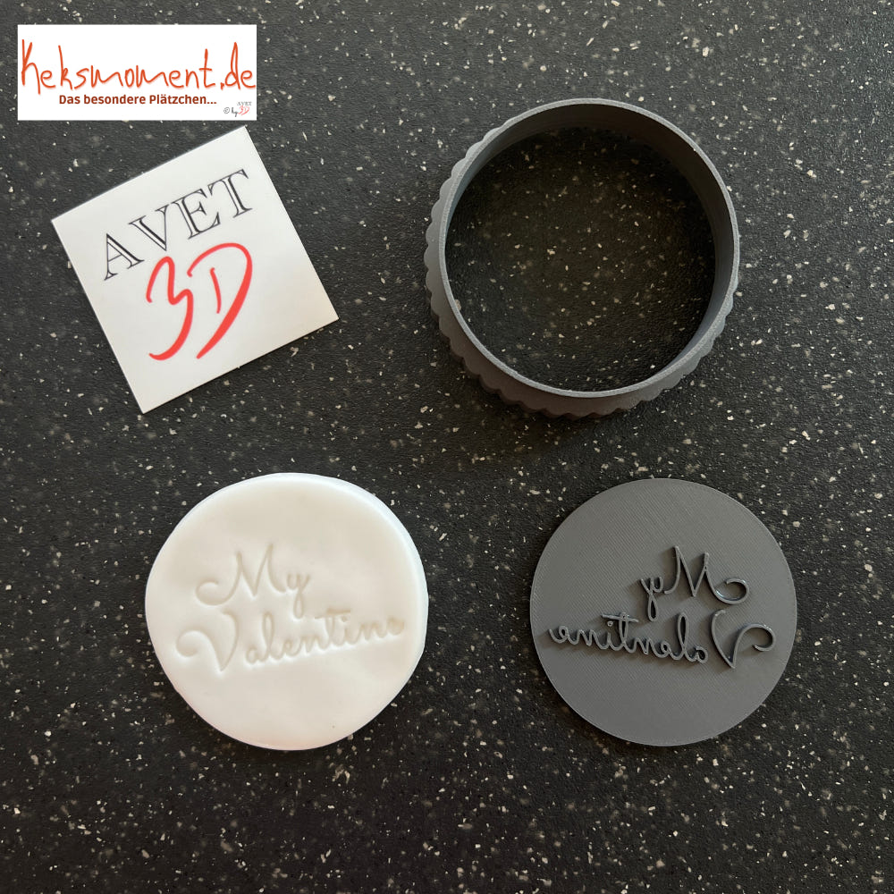 Runder Schriftstempel mit spiegelverkehrtem Valentinsgruß neben einer hellen geprägten Scheibe und rundem Ausstechring.