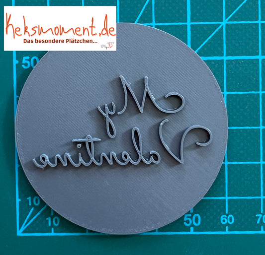 Runde Stempelplatte von oben mit erhabenem spiegelverkehrtem Schriftzug „My Valentine“ auf einer Rastermatte.
