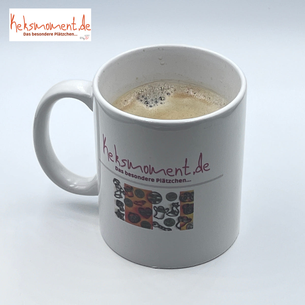 Weiße bedruckte Tasse mit Henkel und schaumigem Getränk, schräg von oben ohne Hasenmotiv.